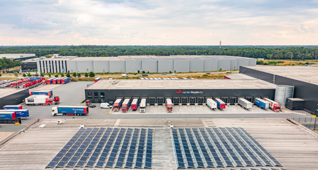 Bedrijventerrein met zonnepanelen en vrachtwagens, waar gebruik gemaakt wordt van Firan energiehub.