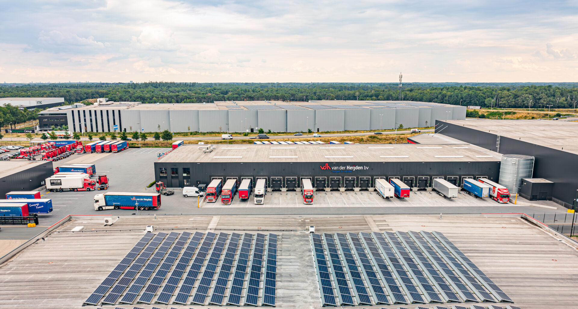 Bedrijventerrein met zonnepanelen en vrachtwagens, waar gebruik gemaakt wordt van Firan energiehub.