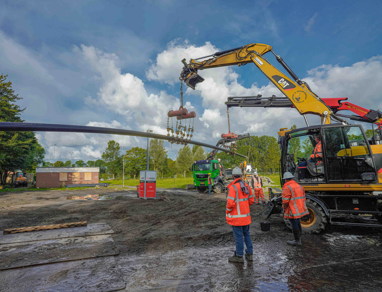 Foto graafmachines en monteurs plaatsen warmteleiding bij warmtenet aanleg in Zaanstad.